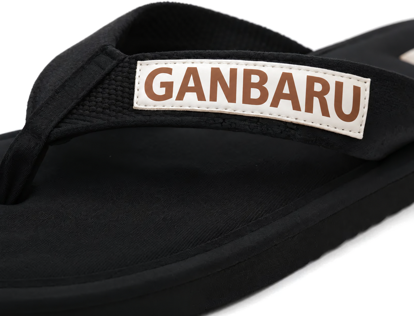 Nawemo Ganbaru Zimtlatschen – Schwarz Cinnamon slippers Nawemo 'Ganbaru' in modern design with black strap and brown lettering.